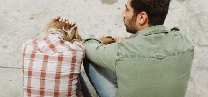 Distressed Woman and Man Sitting on the Sidewalk