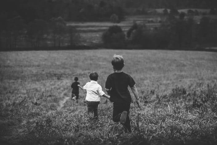three boys running in field