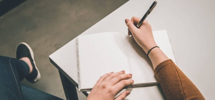 man writing in his notebook
