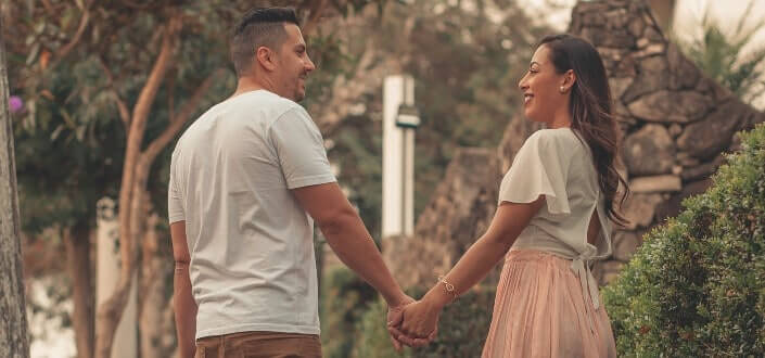 Happy couple facing each other while holding hands