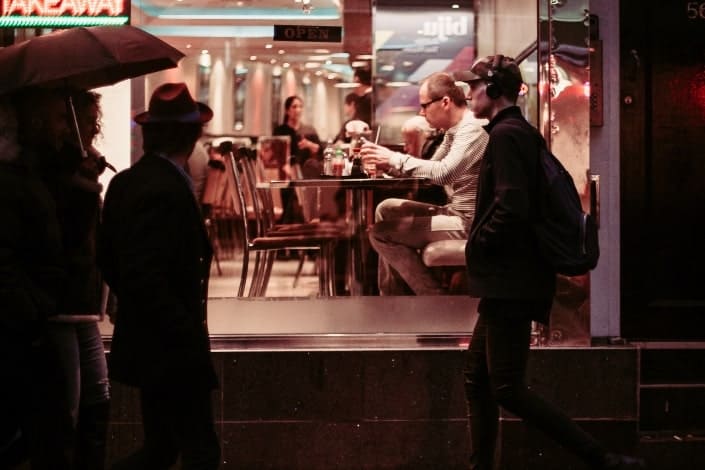 Man walking past a busy cafe