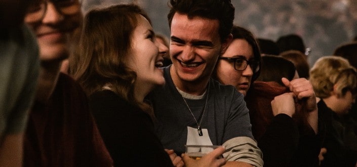 Guy intently smiling at girl amidst crowd