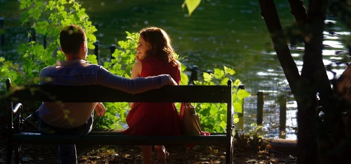 Couple sitting on a bench in front of a lake