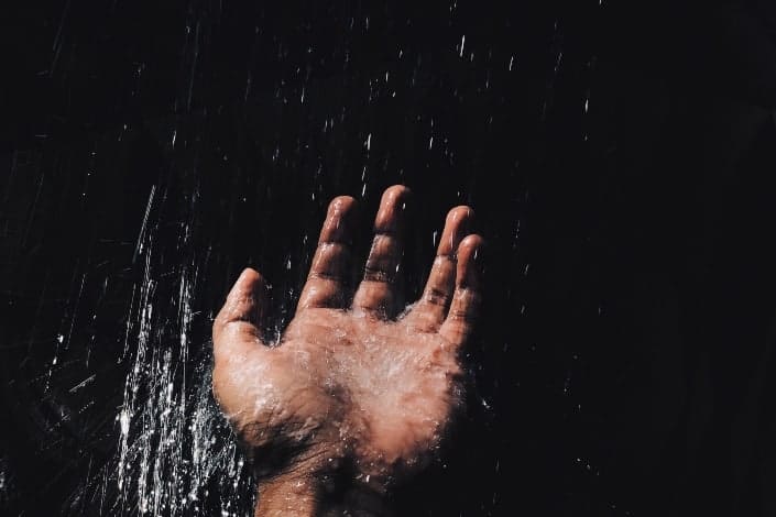 Hand holding out to touch water.