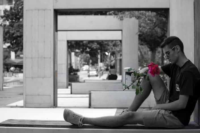 Guy holding a red rose.