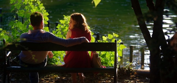 Couple sitting on a bench overlooking lake.