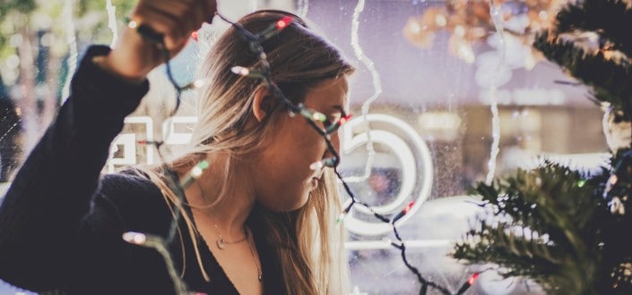 side view of a woman holding christmas lights