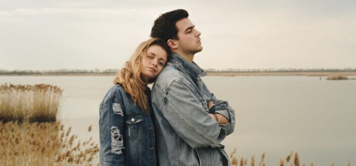 woman leaning on a man from behind near a lake