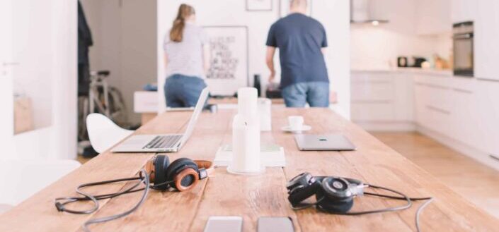 laptops and headsets on a table with man and woman on the background
