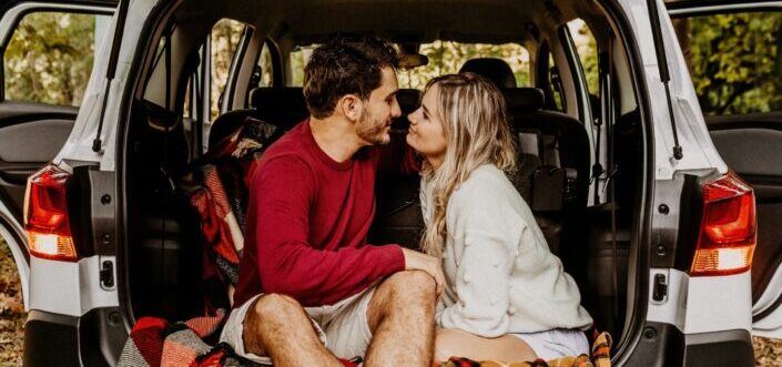 Sweet couple having intimate moment at the car's rear compartment.