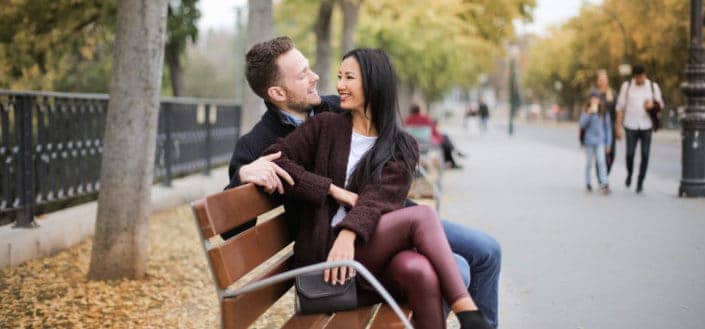 Couple Sitting On Wooden Bench