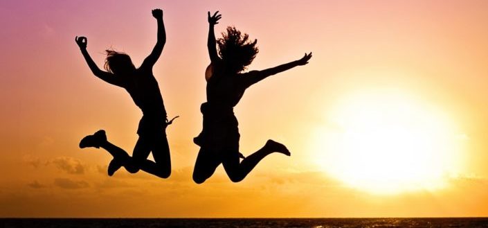 Silhouette of two people jumping