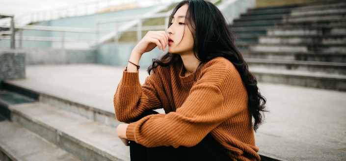 woman sitting on concrete bench thinking