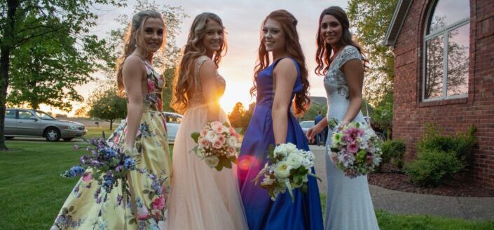 four women smiling while holding flowers 