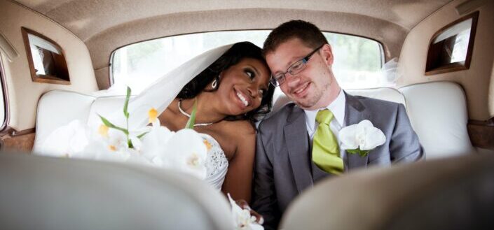 bride and groom sitting closely in the backseat of a car