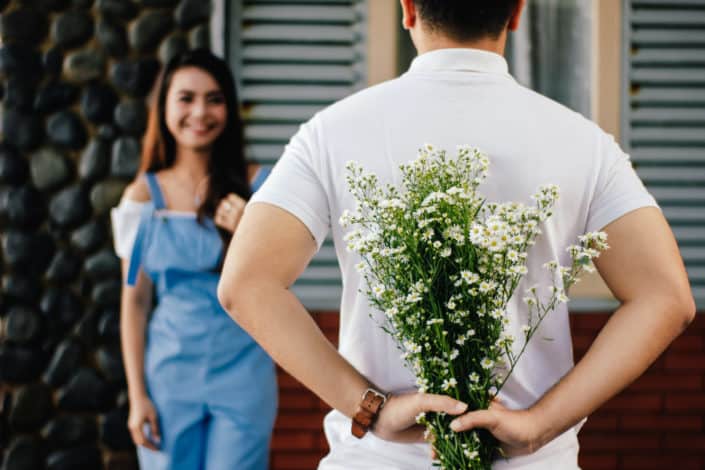 man hiding a flowers to surprise her