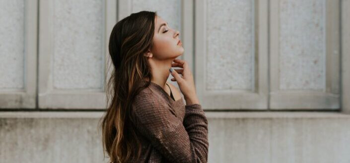 woman with closed eyes touching her neck