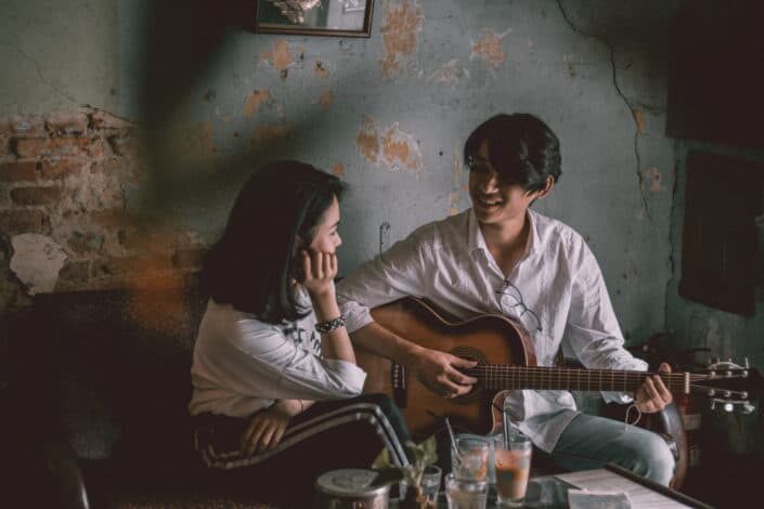 Man playing guitar while taring at the girl.