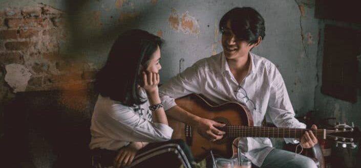 Man playing a guitar song to a woman