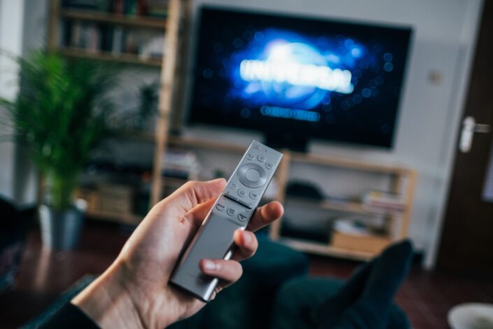 Remote being held by a left hand.
