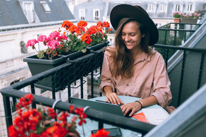 Lady, smiling while doing something on her laptop.