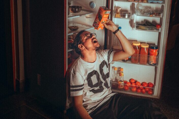 Man, emptying the juice box beside the fridge.