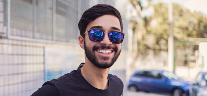 Guy with sunglasses sweetly smiling.