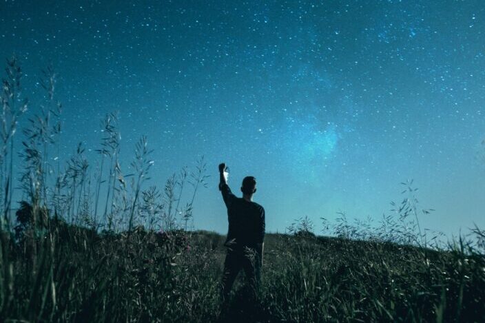 Guy with a lantern standing on a field.