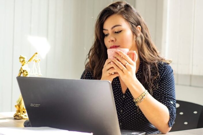 Girl, having coffee, watching something on her latop.