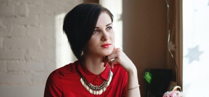 Woman in red, looking away, reflecting.