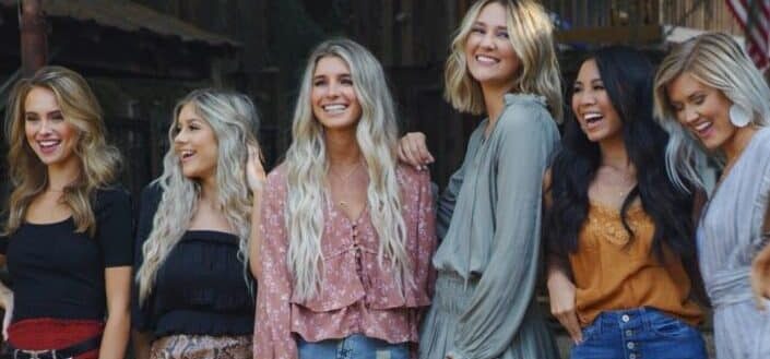 Six girls joyfully pose beside each other.
