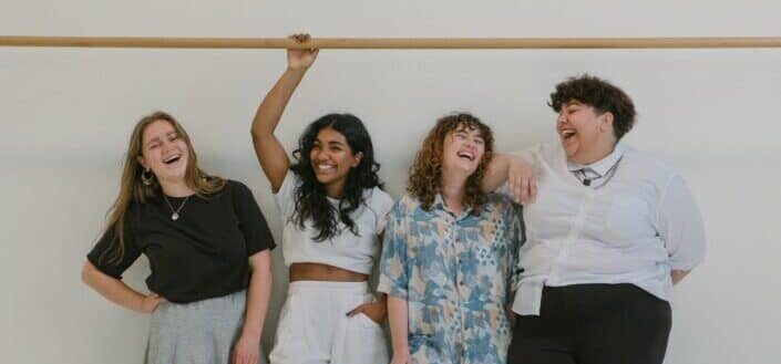Girls standing against a wall, laughing.