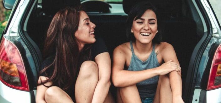 Bestfriends chatting at the back of a car.