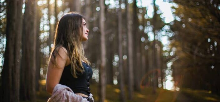 Girl, standing in the middle of the woods.