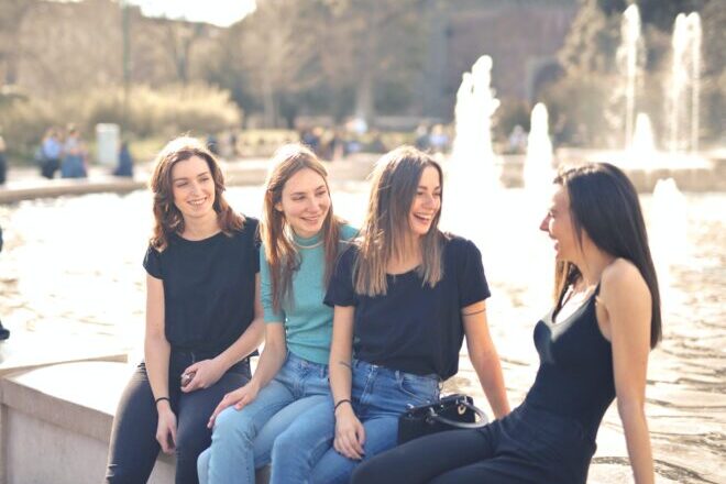 Girl friends sharing laughter beside a fountain. - deep questions to ask