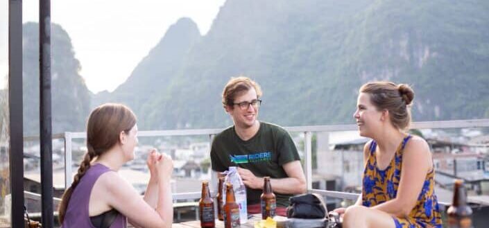 Friends, chatting over bottles of beer, overlooking a magnificient view.