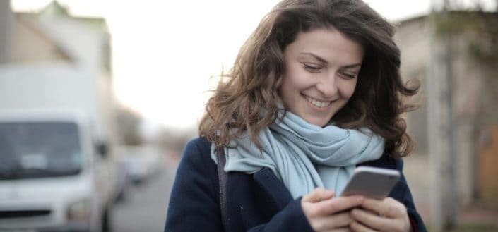 Woman smiling while looking at her phone