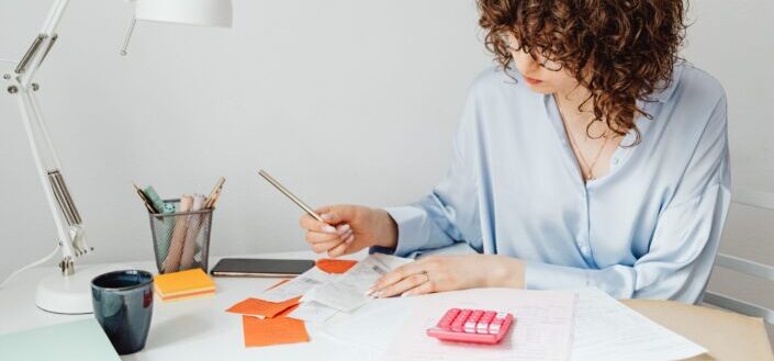 woman-checking-receipts-on-wooden-table-