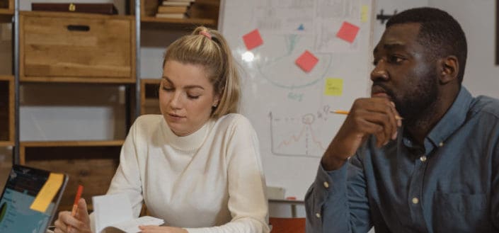 Man listening attentively and woman taking notes in a meeting