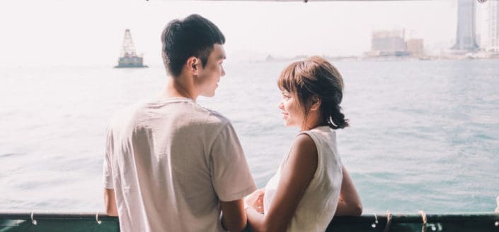 Couple facing each other overlooking the sea
