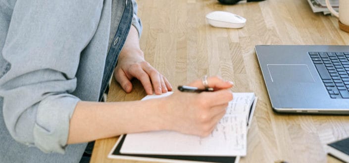 A man taking notes in front of his laptop