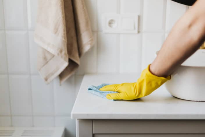 Hand with glove cleaning a table