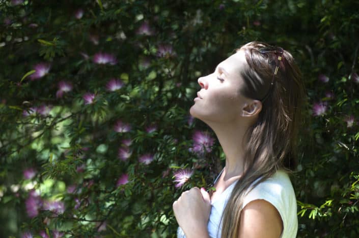 A woman with her eyes closed in a garden