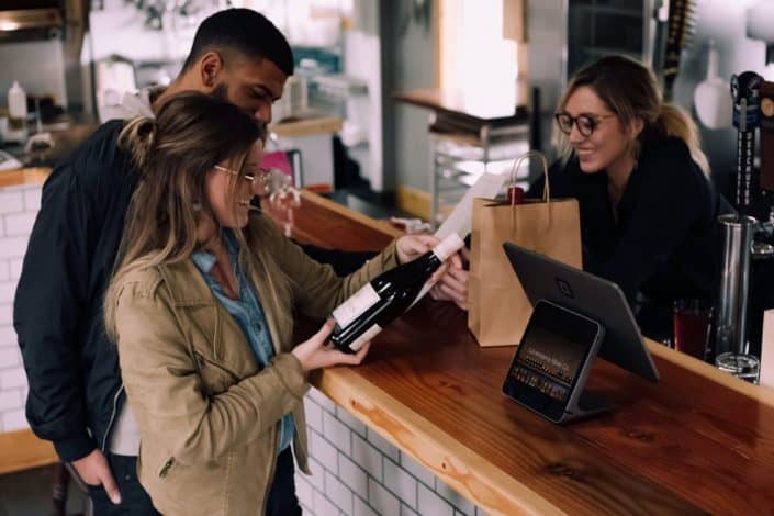 A couple paying for a bottle of wine