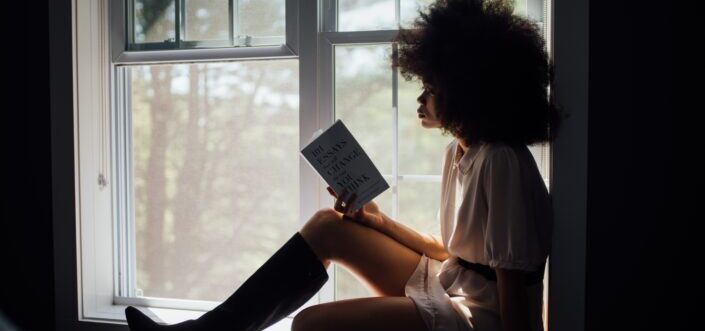 Silhouette of a woman reading a book.