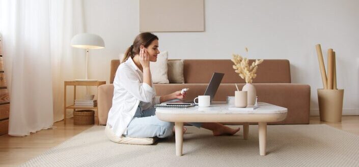 A woman sitting on the floor working on her laptop
