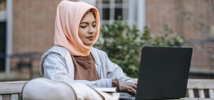 student typing on laptop at table in garden