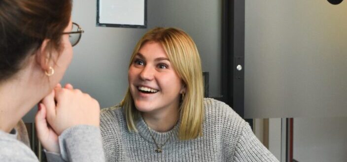 A blonde woman smiling to her friend
