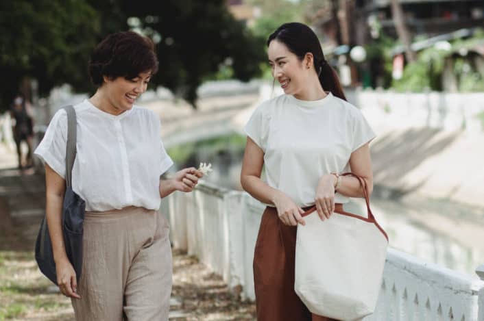 Two stylish girls walking on street and smiling
