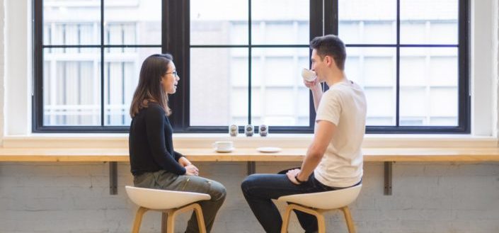 Couple having coffee on a bar in front of window